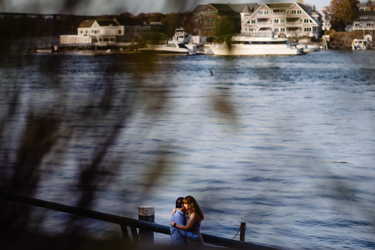 Landscape style image of river with a couple hugging in the bottom of the image frame.