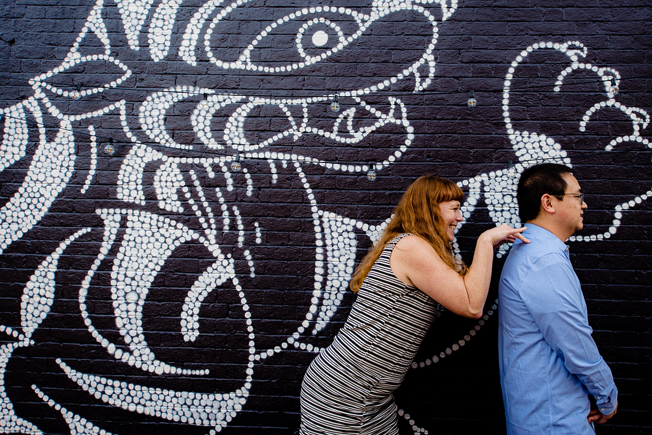 Couple in front of mural in Portsmouth NH. She is sneaking up on him.