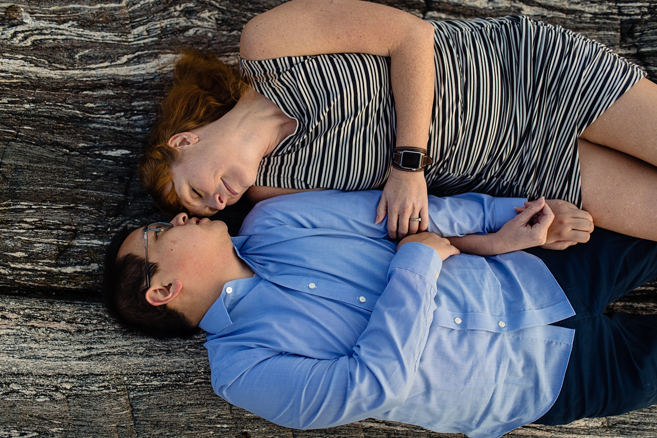 Couple laying down and snuggling on a rock