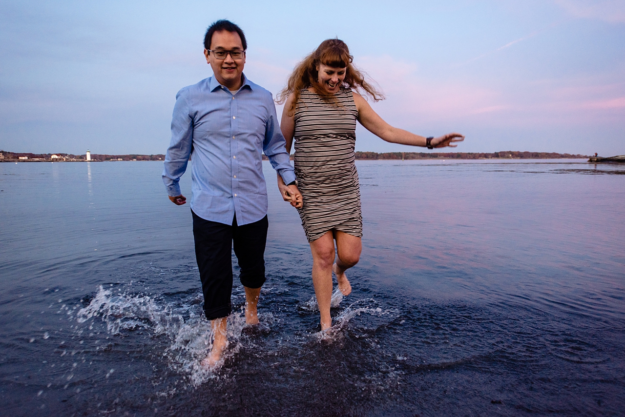 couple frolicing out of the water, slight motion blur, blue and purple sunset in the background