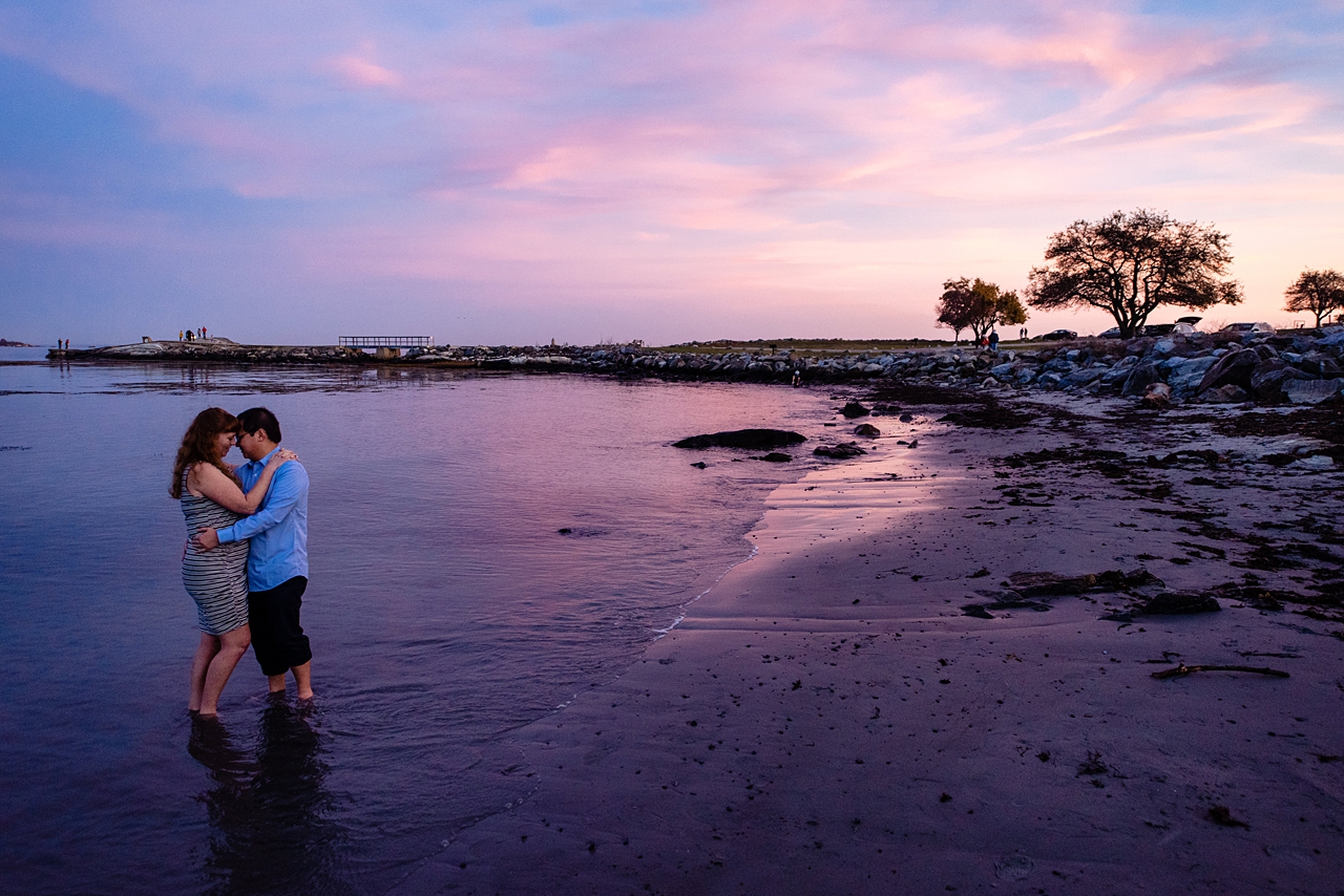 Purple and Blue sunset image with couple ankle deep in the water in an embrace.