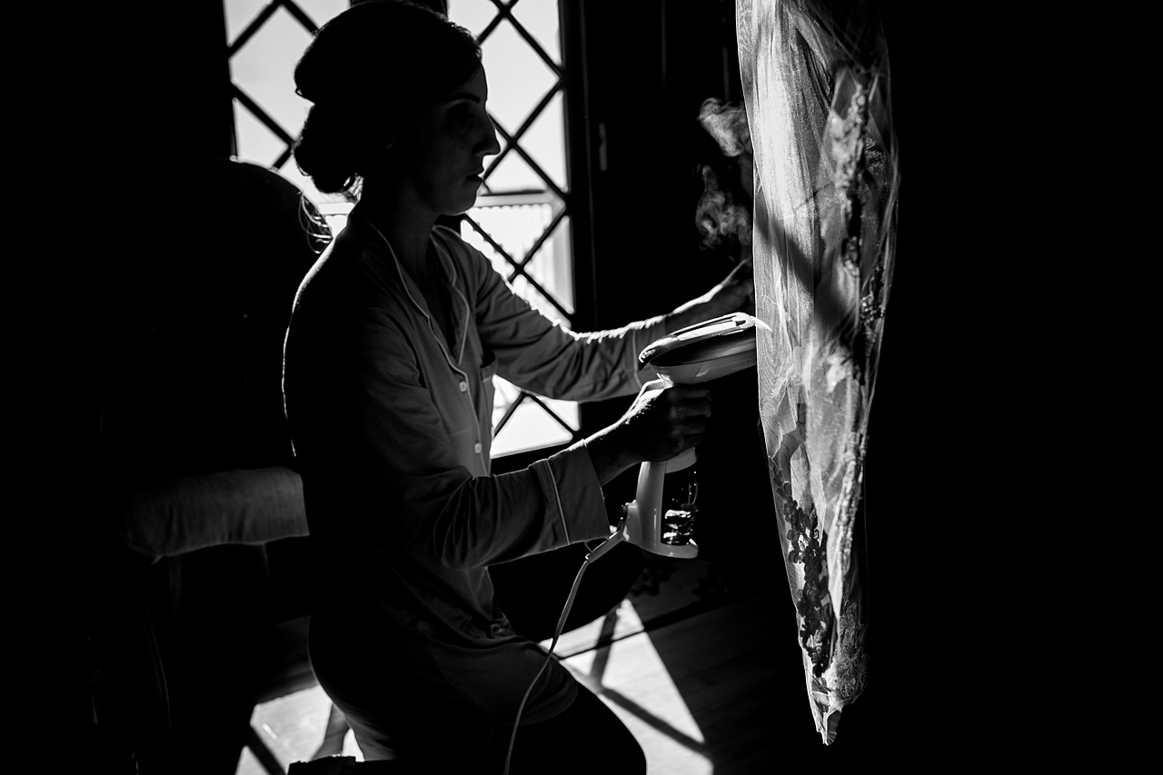 Black and white photo of bridesmaid steaming a wedding veil. 