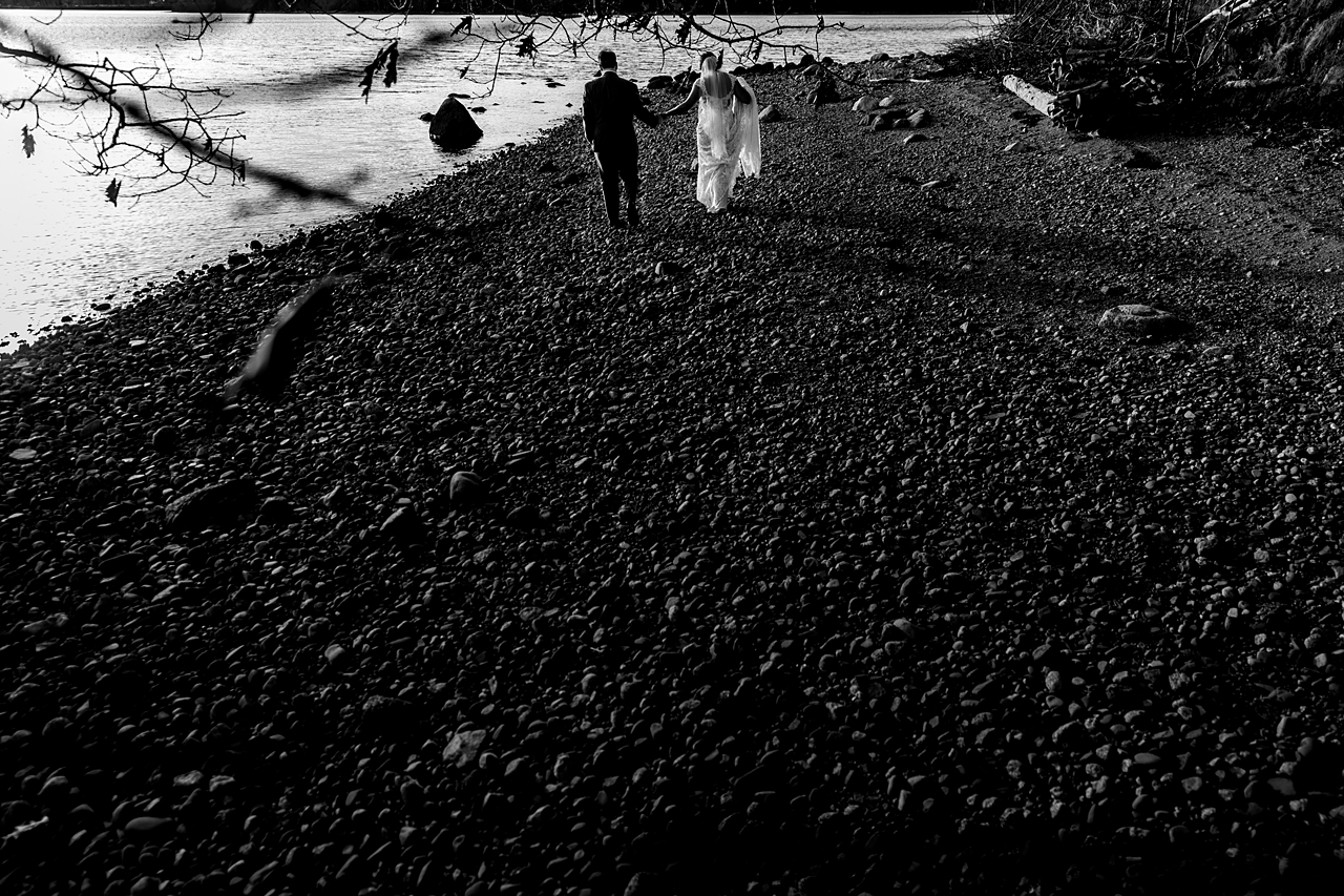 high contrast black and white photo of couple walking away hand in hand. They are at the top of the image frame