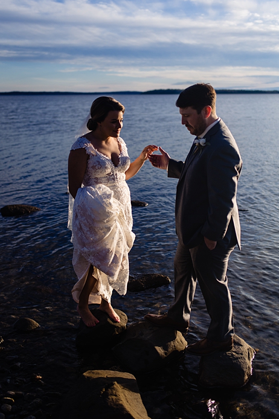 the moment right before the bride takes her grooms hand for help walking on rocks in water