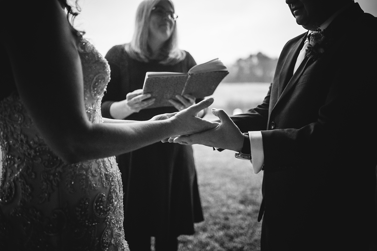 black and white photo of a couple holding hands during their wedding ceremony.