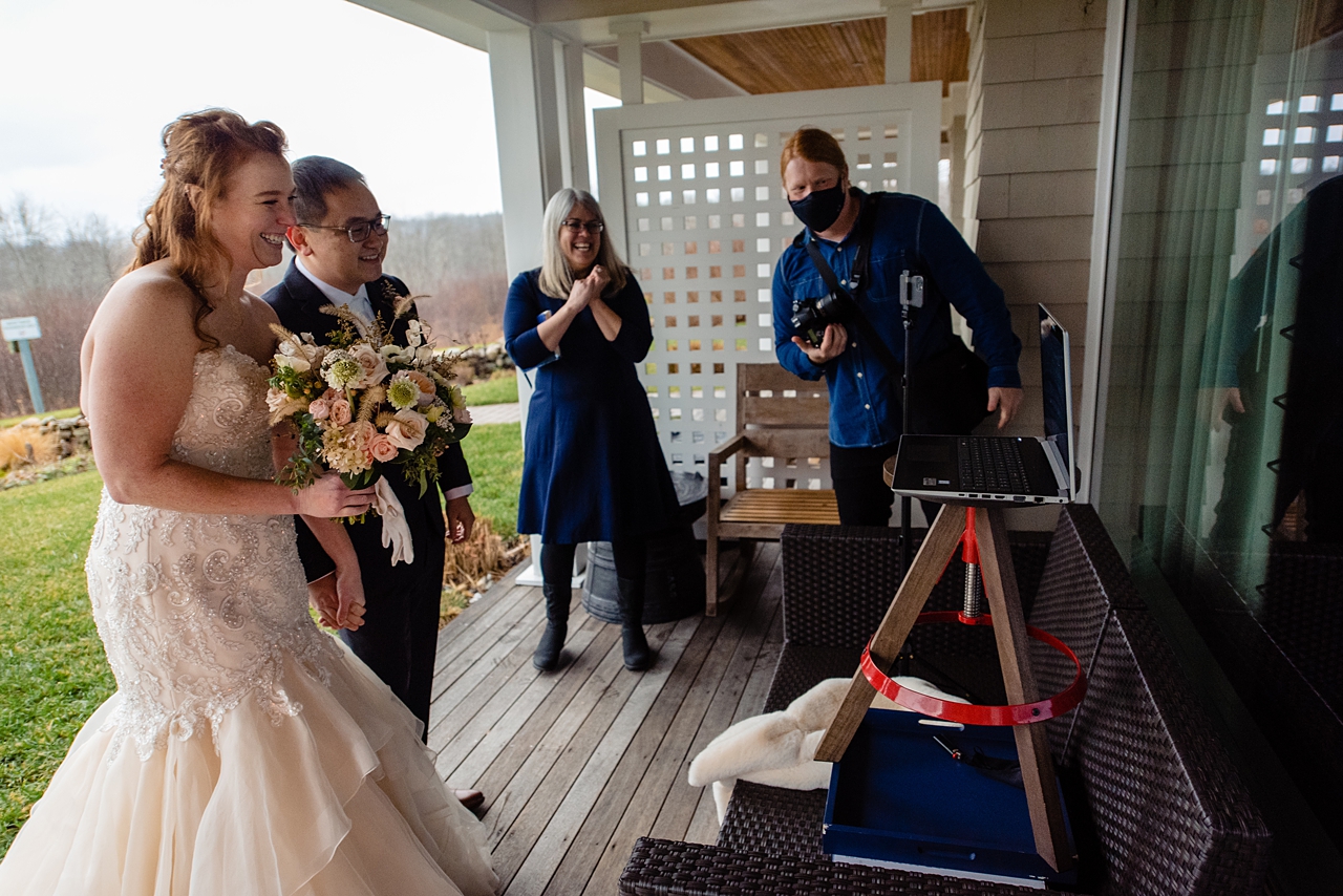 Small wedding group looking at a laptop to say hi to guests zooming in.