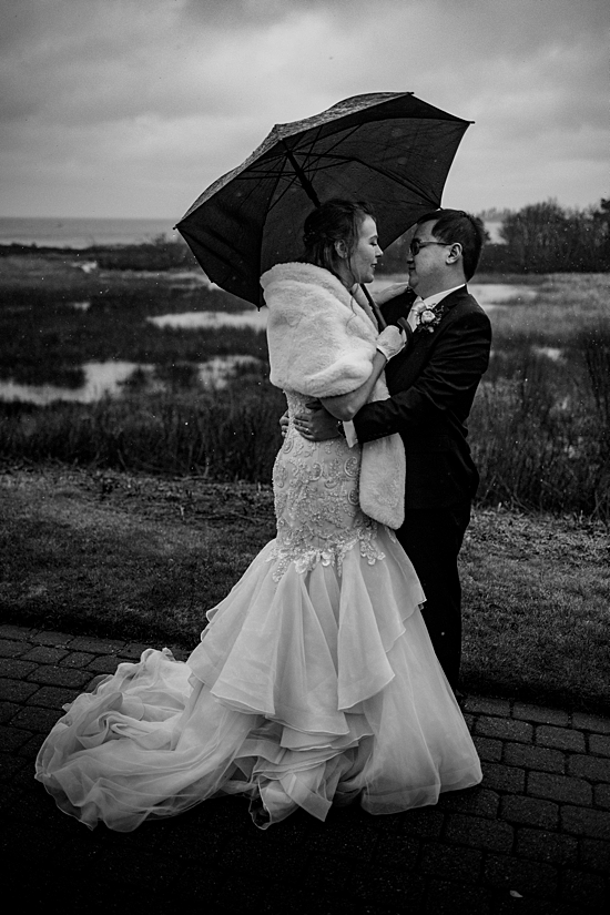 Wedding couple outside in the rain with umbrella.
