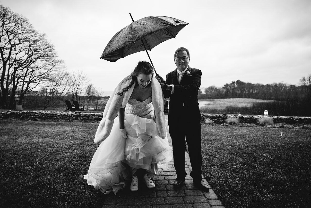 Black and white photo of wedding couple with an umbrella.